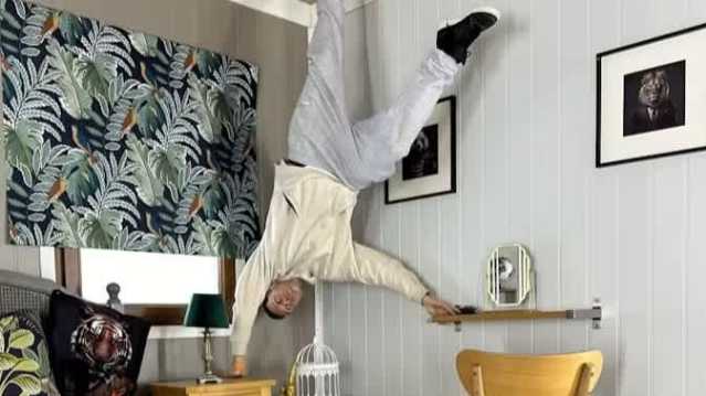 man standing upside down in a bedroom 