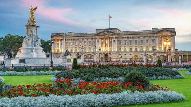 Front view of Buckingham Palace and Victoria Memorial with colourful gardens.