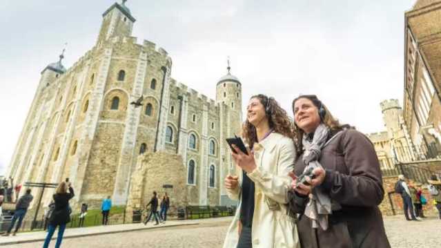 Tourists taking photos near the medieval walls of the Tower of London