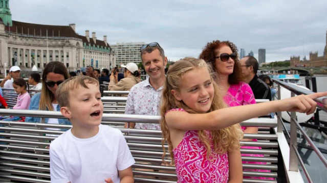 Family with children enjoying the open‑air deck of the London Eye River Cruise, pointing at landmarks