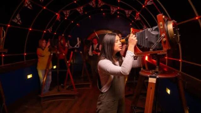 Visitors operate vintage cameras in a steampunk-inspired set at Jeff Wayne’s War of the Worlds immersive attraction, offered with Jeff Wayne’s War of the Worlds tickets.