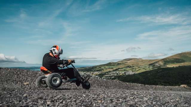 Quarry Karts rider racing downhill at Zip World Penrhyn with mountain views