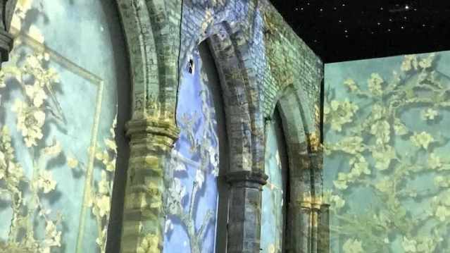 Projection of Van Gogh’s Almond Blossom fills a stone archway with soft blue backgrounds and delicate white flowers wrapping around cathedral walls.